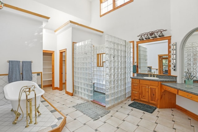 bathroom featuring a bathing tub, a high ceiling, vanity, and a healthy amount of sunlight