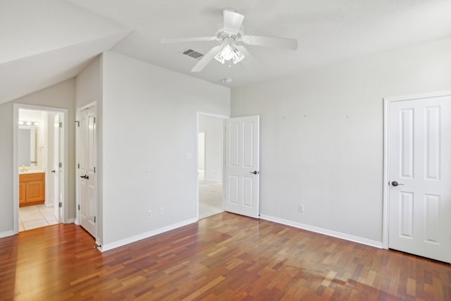 unfurnished bedroom featuring connected bathroom, ceiling fan, light hardwood / wood-style flooring, and lofted ceiling