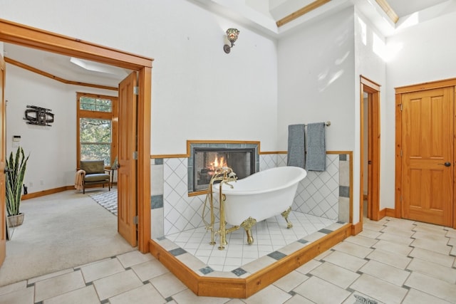 bathroom with a tub to relax in, tile walls, crown molding, and a tiled fireplace