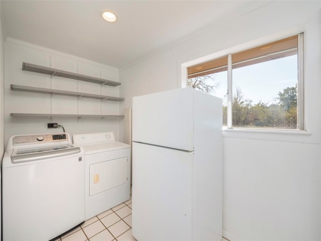 laundry area featuring washing machine and dryer, a healthy amount of sunlight, and light tile patterned flooring