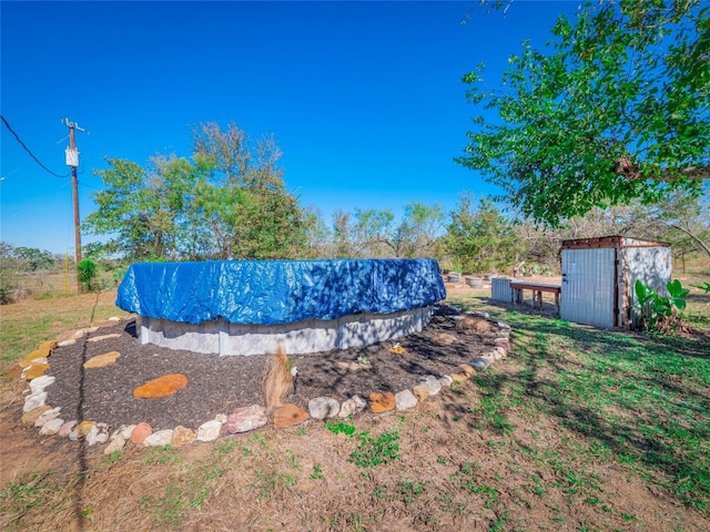 view of yard featuring a storage unit and a covered pool