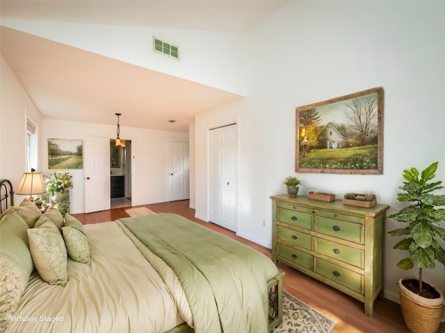 bedroom with vaulted ceiling, a closet, and light hardwood / wood-style flooring