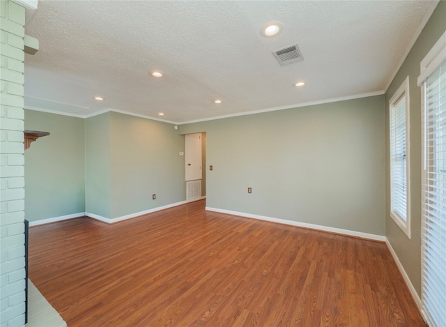 empty room featuring crown molding, wood-type flooring, a textured ceiling, and a brick fireplace