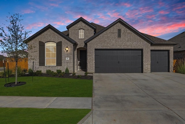 french country home with a yard and a garage