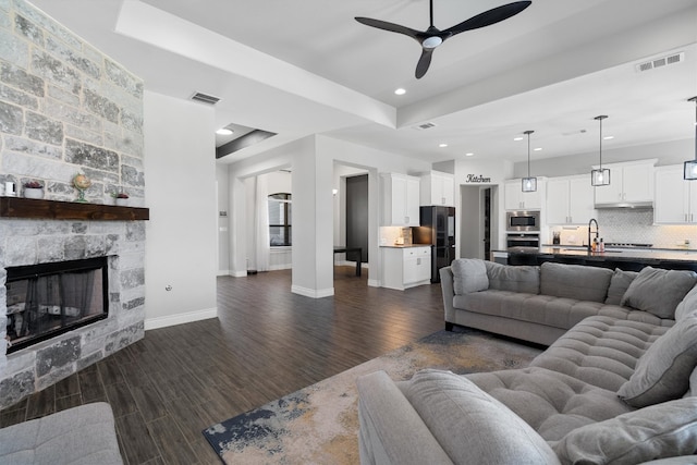 living room featuring dark hardwood / wood-style floors, ceiling fan, sink, and a fireplace