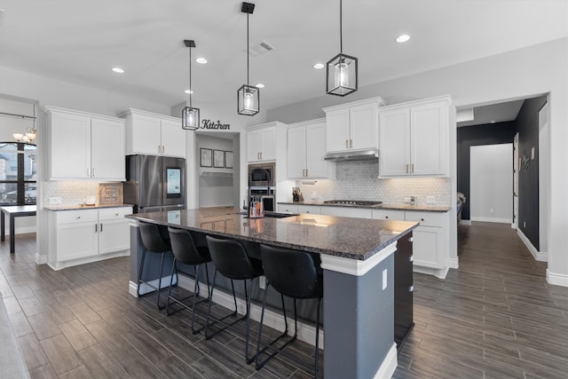 kitchen featuring a center island with sink, a kitchen breakfast bar, white cabinets, appliances with stainless steel finishes, and dark hardwood / wood-style flooring