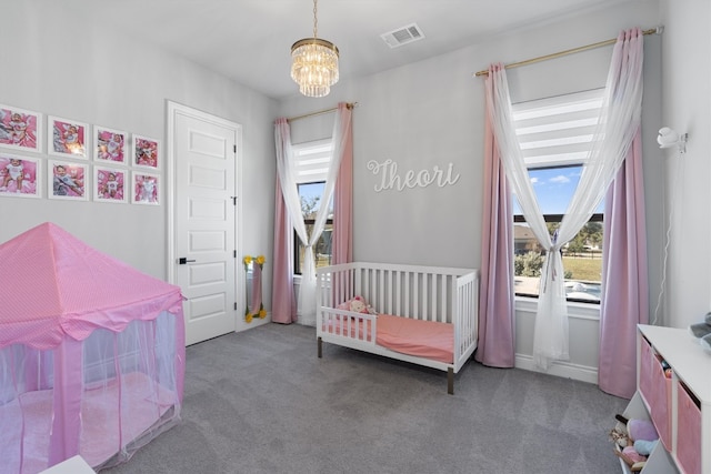 bedroom with a crib, carpet floors, and a chandelier