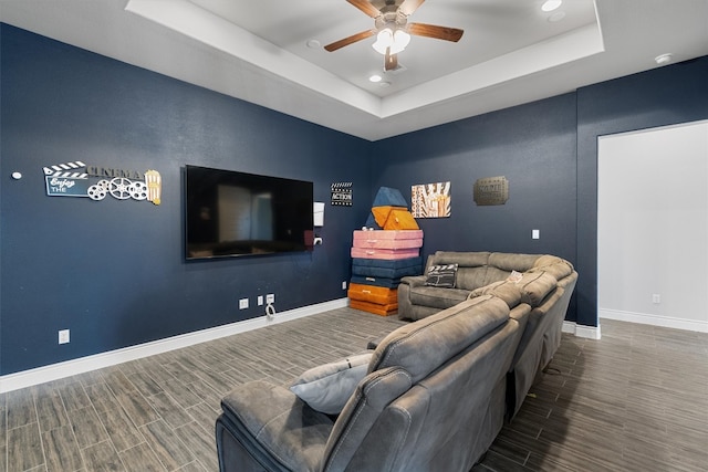 living room featuring dark hardwood / wood-style flooring, a raised ceiling, and ceiling fan