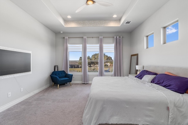 carpeted bedroom with a raised ceiling and ceiling fan