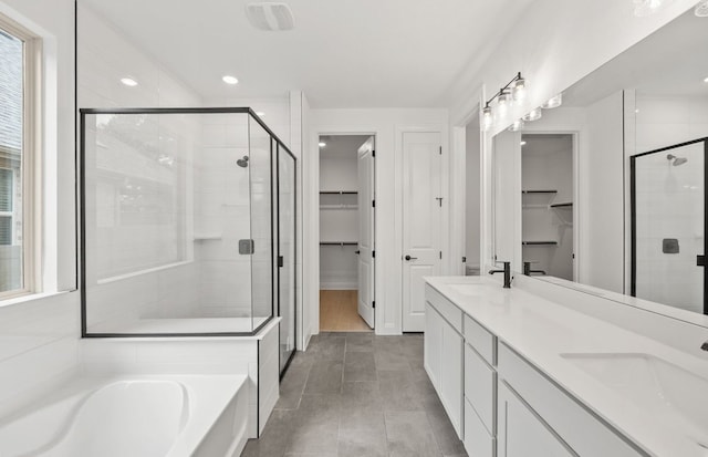 bathroom featuring a sink, a shower stall, a bath, and a spacious closet