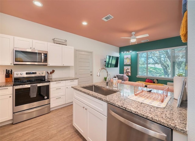 18802 Nicklaus Dr, Lago Vista, TX 78645 - kitchen with stainless steel appliances, a sink, white cabinetry, light wood-type flooring, and ceiling fan