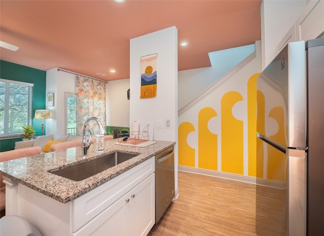 kitchen featuring light stone countertops, stainless steel appliances, sink, white cabinets, and light hardwood / wood-style floors