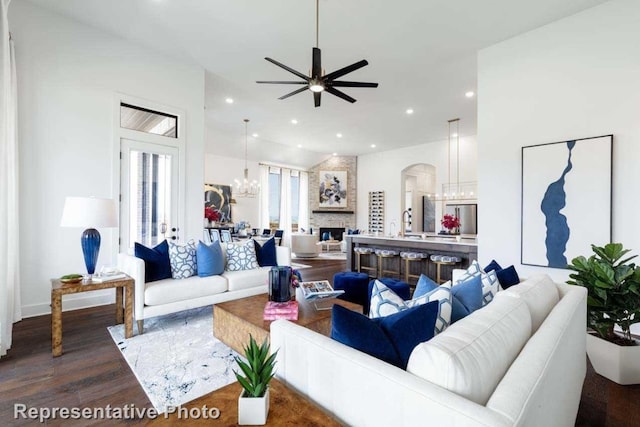 living room featuring ceiling fan with notable chandelier, wood-type flooring, and a fireplace