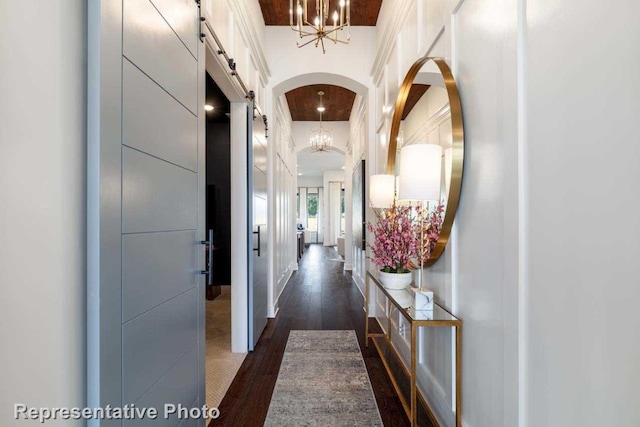 hallway featuring a towering ceiling, a barn door, and dark wood-type flooring