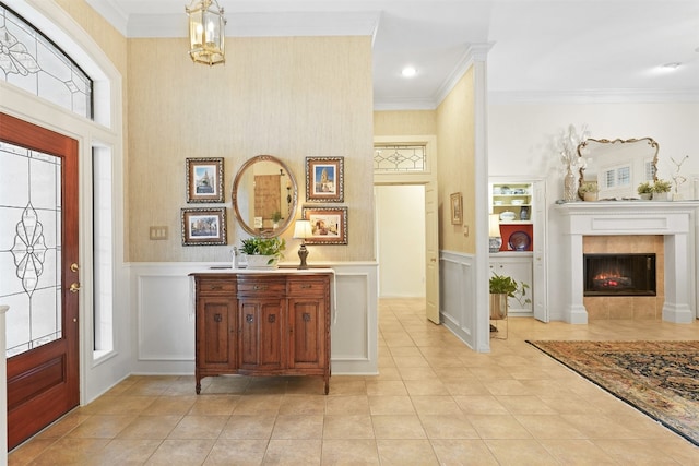 foyer entrance featuring a tiled fireplace, a healthy amount of sunlight, and ornamental molding