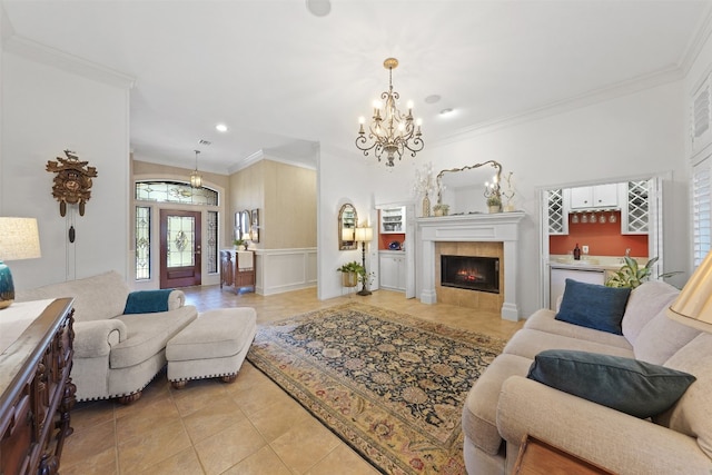 living room featuring light tile patterned floors, crown molding, a tile fireplace, and a chandelier