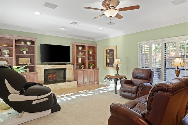 living room with light colored carpet, a stone fireplace, ceiling fan, and crown molding