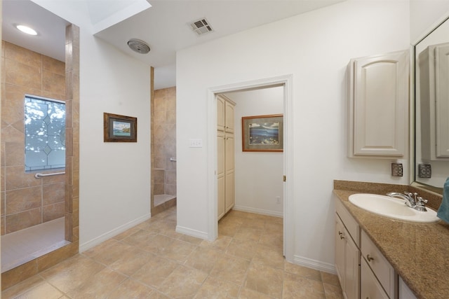 bathroom featuring a tile shower, tile patterned flooring, and vanity