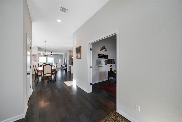 hall with a chandelier and dark wood-type flooring