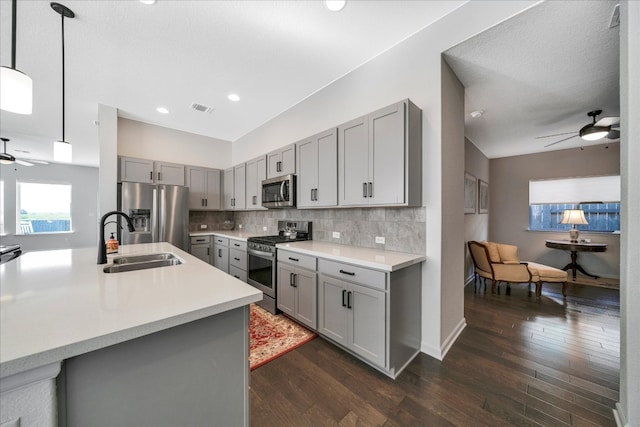 kitchen featuring gray cabinetry, dark wood-type flooring, stainless steel appliances, and decorative light fixtures