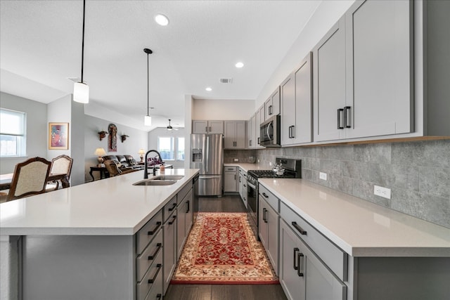 kitchen featuring sink, dark hardwood / wood-style floors, pendant lighting, a kitchen island with sink, and appliances with stainless steel finishes