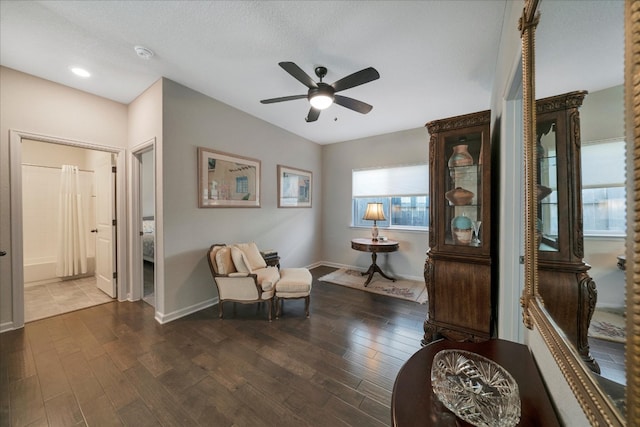 living area with a textured ceiling, dark hardwood / wood-style floors, and ceiling fan