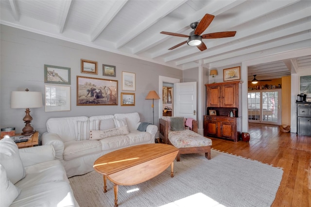 living room with ceiling fan, beamed ceiling, and light wood-type flooring