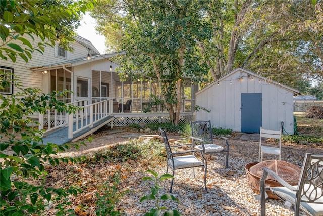 view of yard featuring a sunroom, a storage unit, an outdoor fire pit, and a wooden deck