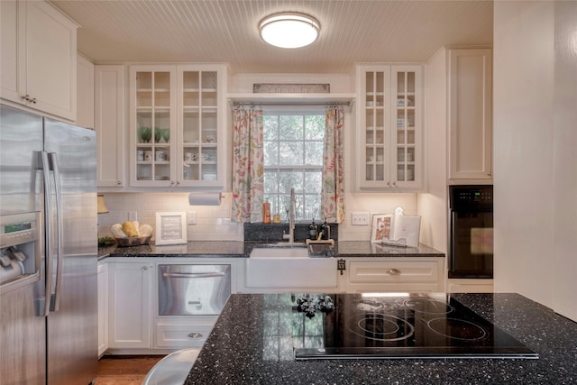 kitchen featuring black appliances, dark stone countertops, white cabinetry, and sink