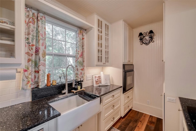 kitchen featuring tasteful backsplash, black oven, sink, and white cabinets