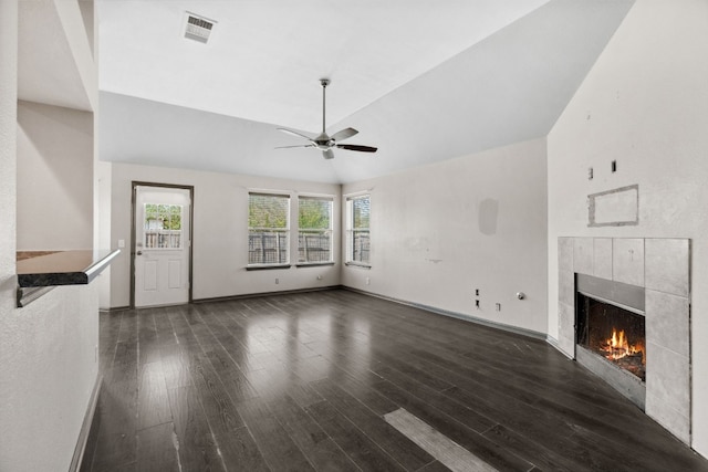 unfurnished living room with dark hardwood / wood-style floors, vaulted ceiling, ceiling fan, and a tiled fireplace