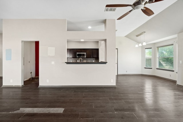 unfurnished living room with ceiling fan with notable chandelier, dark hardwood / wood-style floors, and high vaulted ceiling