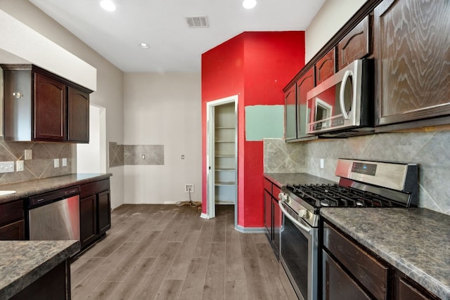 kitchen with hardwood / wood-style floors, backsplash, dark brown cabinets, and stainless steel appliances