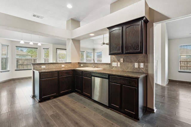 kitchen featuring kitchen peninsula, stainless steel dishwasher, sink, dark hardwood / wood-style floors, and hanging light fixtures