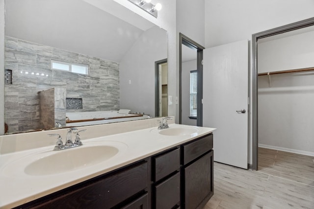 bathroom featuring vanity, wood-type flooring, and vaulted ceiling