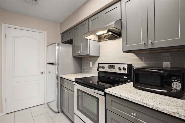 kitchen with gray cabinets, light tile patterned floors, appliances with stainless steel finishes, tasteful backsplash, and light stone counters