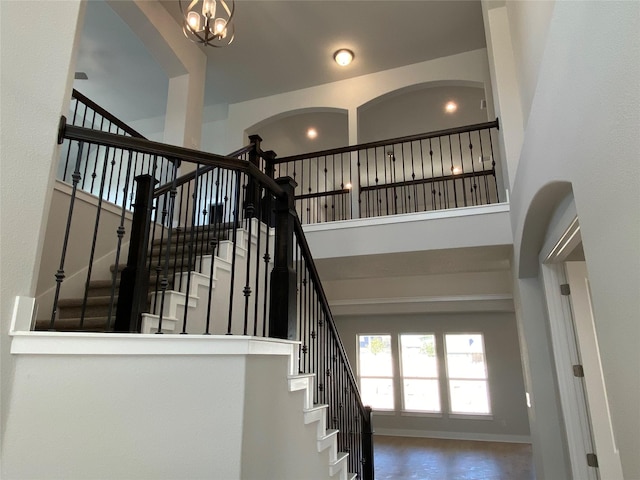 staircase with a towering ceiling and a notable chandelier