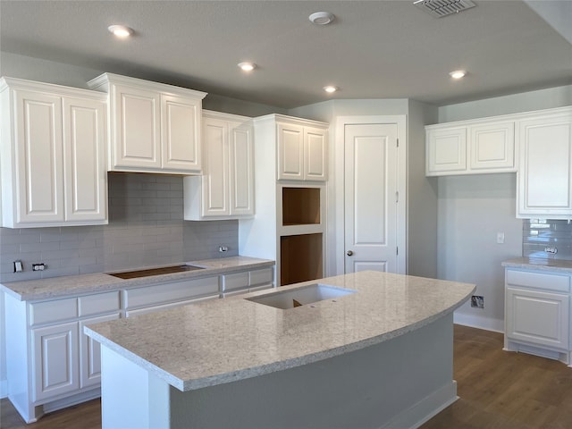 kitchen featuring dark hardwood / wood-style flooring, white cabinets, black electric stovetop, and a kitchen island with sink