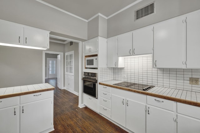 kitchen with white cabinets, dark hardwood / wood-style flooring, tile counters, and black appliances