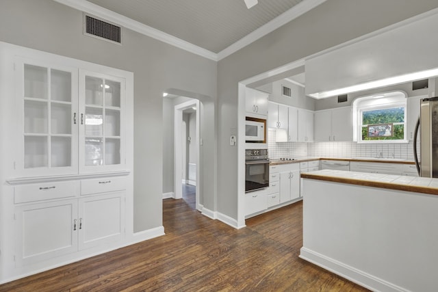 kitchen with white cabinets, appliances with stainless steel finishes, tile countertops, and dark hardwood / wood-style floors