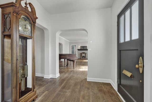 entrance foyer featuring crown molding, a fireplace, and dark hardwood / wood-style floors