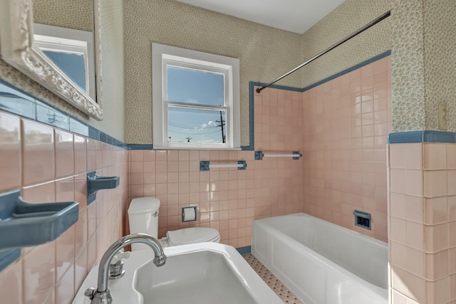 full bathroom with tiled shower / bath, toilet, sink, and tile walls