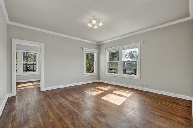 spare room with plenty of natural light, dark hardwood / wood-style flooring, crown molding, and a chandelier