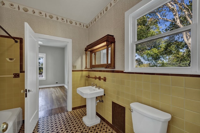 bathroom featuring wood-type flooring, toilet, tile walls, and a healthy amount of sunlight