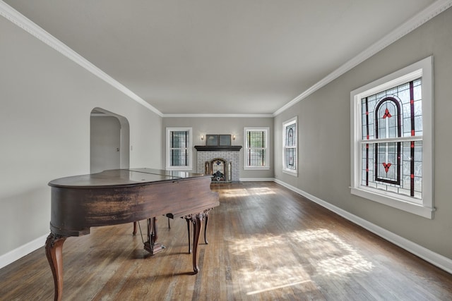 game room featuring dark hardwood / wood-style floors, crown molding, and a brick fireplace