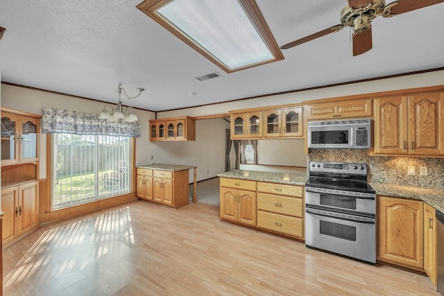 kitchen with pendant lighting, light stone counters, backsplash, and appliances with stainless steel finishes