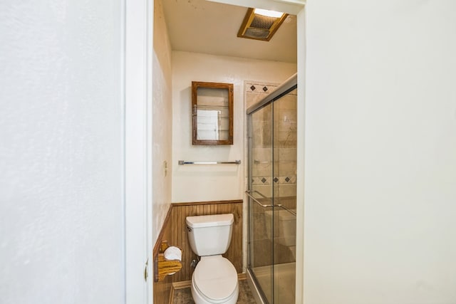 bathroom with toilet, walk in shower, and wooden walls