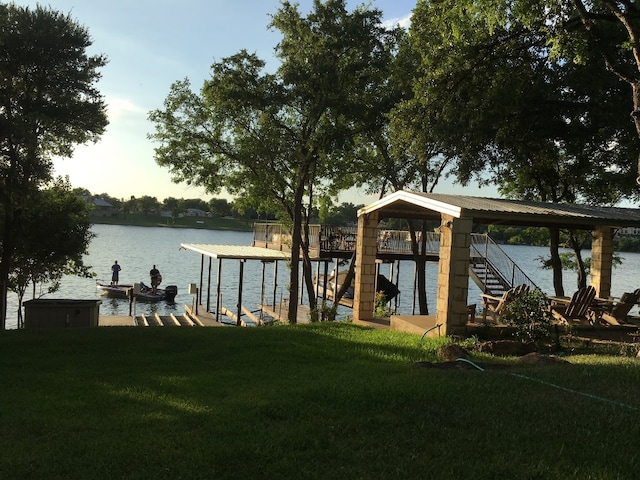 view of dock with a yard and a water view