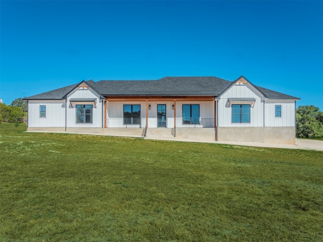 rear view of property featuring a lawn and covered porch