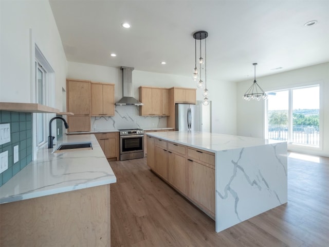 kitchen with wall chimney exhaust hood, a kitchen island, stainless steel appliances, and decorative light fixtures